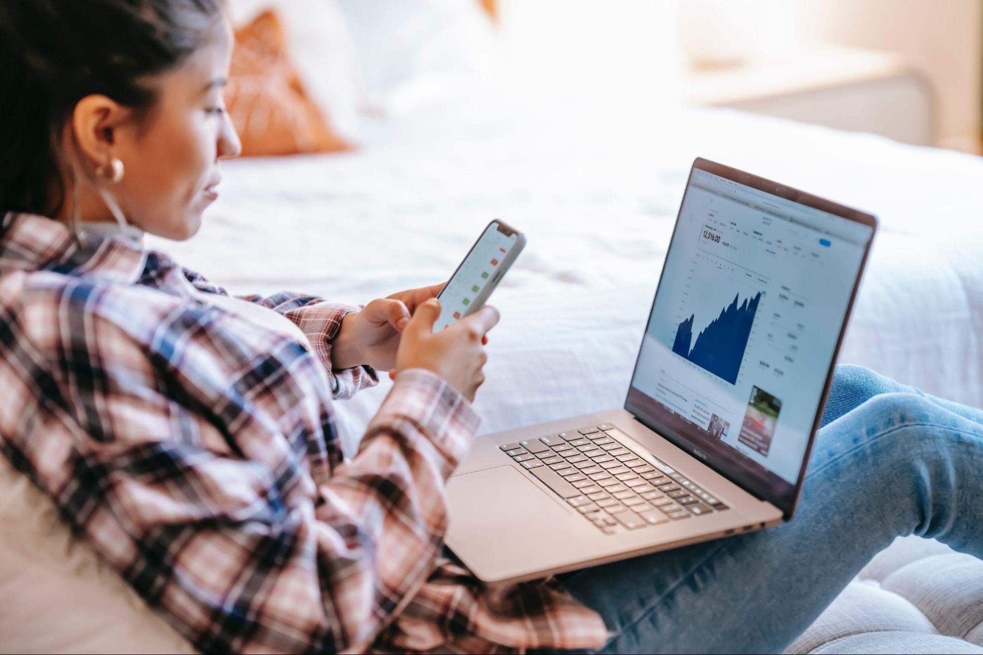 female trader viewing the chart on her laptop and mobile phone