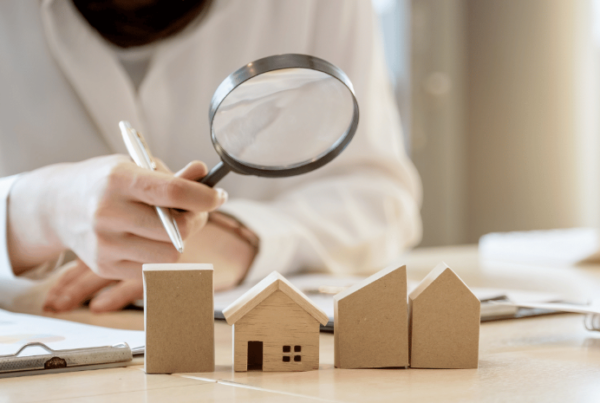 A person looking at wooden toy houses through a magnifying glass