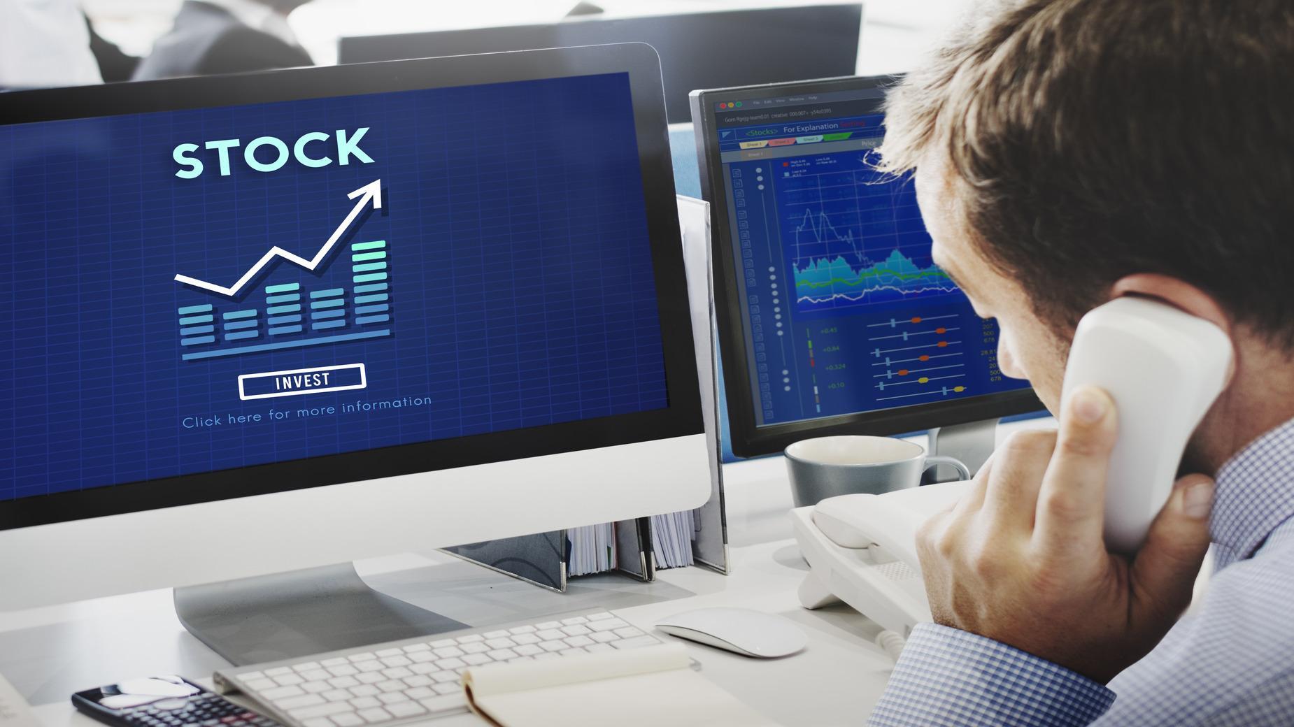Computer monitor showing the word stock and a person taking a call