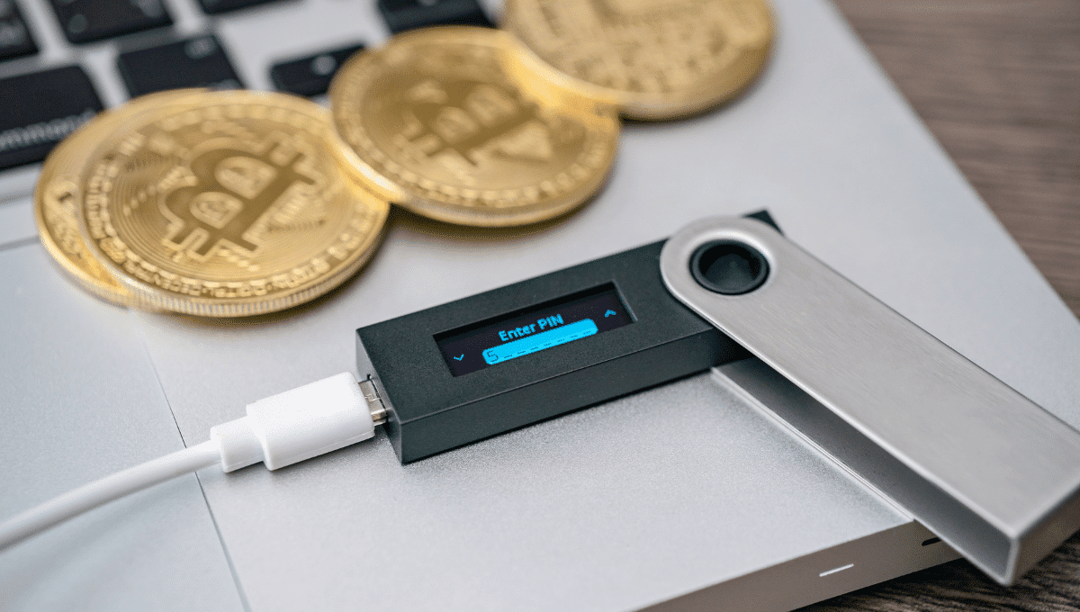closeup of a hardware wallet with crypto coins beside it