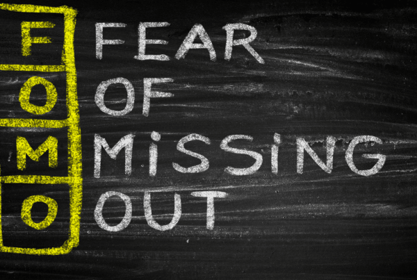 A Blackboard with FOMO written vertically in yellow and "Fear of missing out written horizontally in white to spell out the meaning